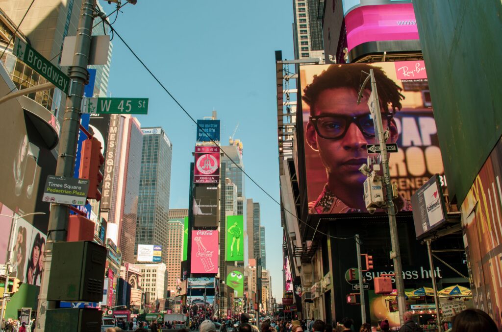 Lively daytime scene in Times Square, New York, showing towering skyscrapers and vibrant billboards.